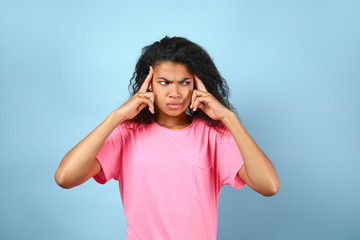 Thoughtful young African-American woman on color background