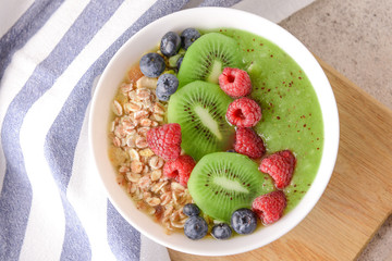 Bowl with tasty oat flakes and fruits on table
