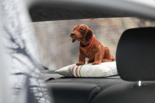 brown bobble head dog is sitting in the parcel shelf of a car