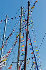 different international nautical flags on the mast of a sailing boat mast are fluttering in the wind © Marion