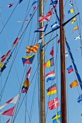 different international nautical flags on the mast of a sailing boat mast are fluttering in the wind