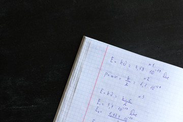 copybook abstract with solving physics problems on a black board background. exam preparation