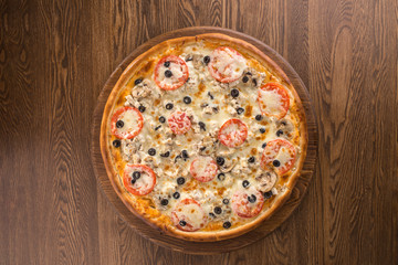 Italian Pizza with olives, sliced mushrooms, tomato sauce and cheddar isolated on wooden background