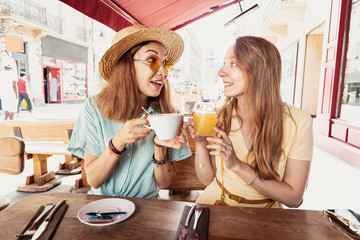 Close up shot of female friends drinking coffee and juice in cafe