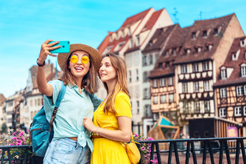 Two multicultural girl friends take a selfie on smartphone while traveling in European old cities. Vacation and relationship concept