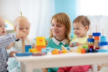 Obraz na płótnie Canvas Nursery babies playing with teacher in the classroom