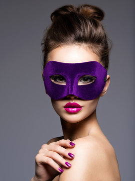Portrait of a beautiful  woman with purple nails and violet theatre mask on face.