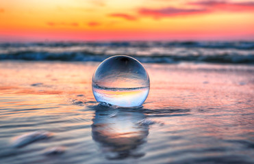 Beautiful sunset on the beach in Slowinski National Park near Leba, Poland. View through a glass, crystal ball (lensball) for refraction photography. Wild, untouched nature.