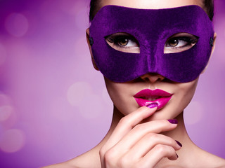 Portrait of a beautiful  woman with purple nails and violet theatre mask on face.