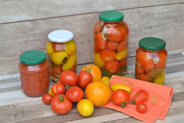 Jar of pickled red and yellow tomatoes on shabby wooden table