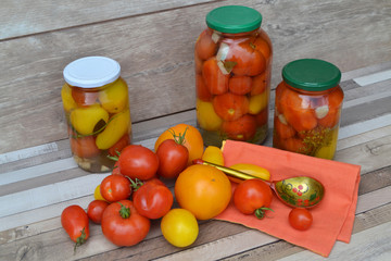 Jar of pickled yellow and red cherry tomatoes on shabby rustic table. Khokhloma style