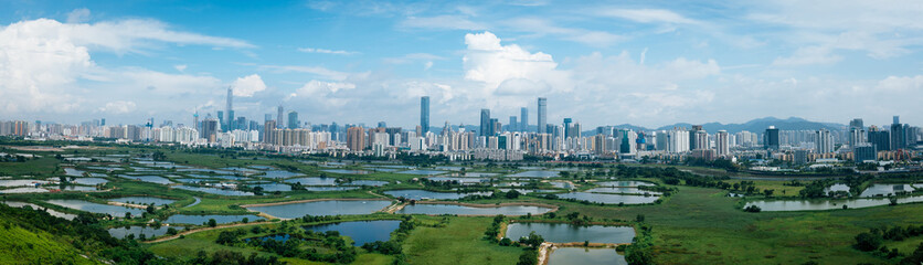 Fototapeta na wymiar Panorama view of rural green fields with fish ponds between Hong Kong and skylines of Shenzhen,China