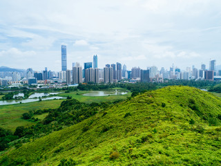 Obraz premium Aerial view of rural green fields with fish ponds on Hong Kong and the skylines of Shenzhen