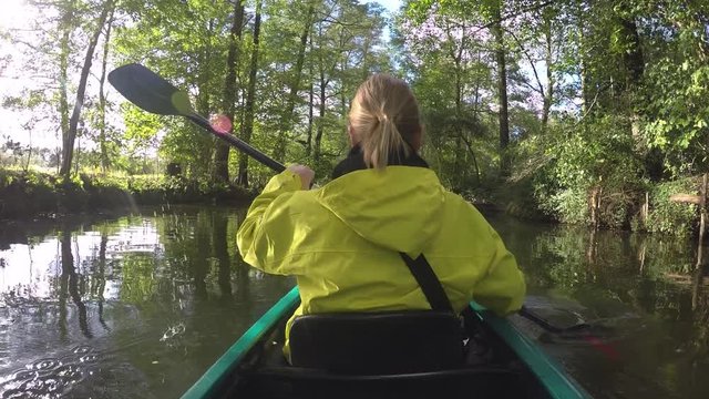 Sports girl with paddle and yellow coat in Kayak surrounded by beautiful nature