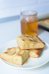 Apple pie on a white plate with honey.