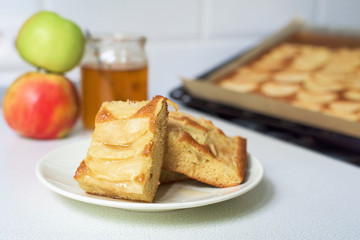 pieces of Apple pie on a white plate with honey.