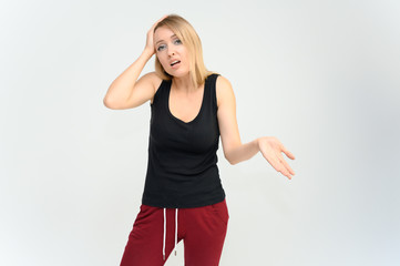 Studio knee-length portrait of a pretty beautiful young happy blonde woman on a white background in a black t-shirt and red trousers. Smiling, talking, showing emotions.