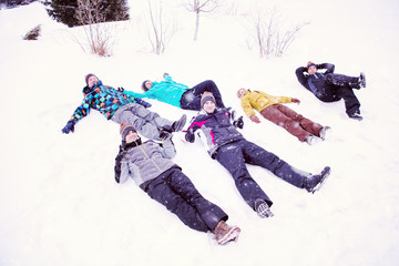 group of young people laying on snow and making snow angel