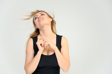 Fototapeta premium Studio waist-length photo portrait of a pretty beautiful young happy blonde woman on a white background in a black t-shirt. Smiling, talking, showing emotions.
