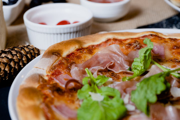close up parma ham pizza with rocket salad on top
