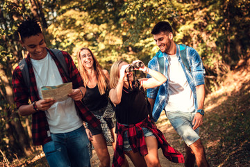 Group of four friends having fun hiking through forest together.