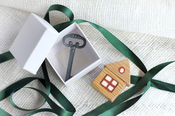box with a key inside and a small wooden house next to the table top view. open holiday gift