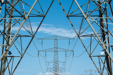 Electricity mast and transmission towers on the background on a blue sky