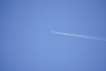 white trace of the plane against the blue sky without clouds. combustion of fuel in the aircraft, emissions. travel concept