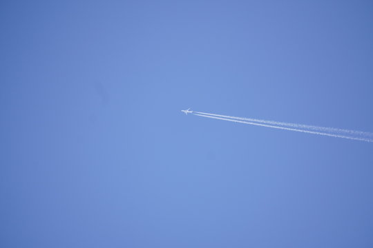 white trace of the plane against the blue sky without clouds. combustion of fuel in the aircraft, emissions. travel concept