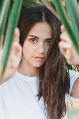 Naklejka premium Beautiful young woman portrait. Portrait on Palm Leaves Background. 