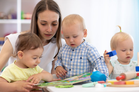 Kindergarten teacher reads book to kids in nursery. Lesson for babies in creche
