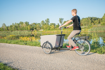 Junger Mann fährt mit Lastenrad, E-Mobilität