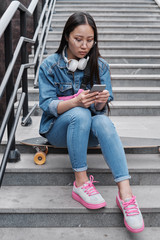Fototapeta na wymiar Korean skater girl with smart phone outdoors