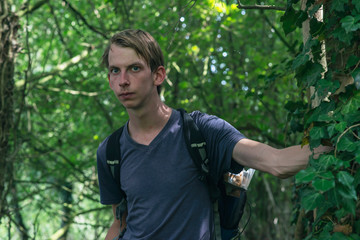 Young man stands in summer forest.