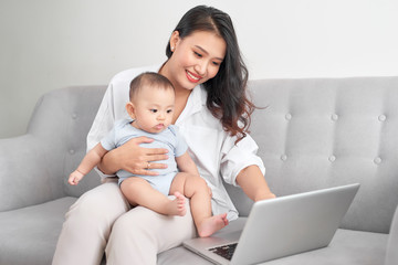Happy family mother and baby at home using laptop computer