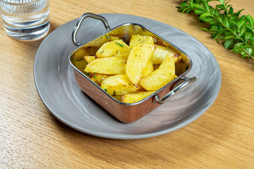 roasted in butter potato wedges with rosemary in golden bowl. Close up. Vegan food. Tasty garnish. Selective focus. Food photo for recipe or menu. Street food