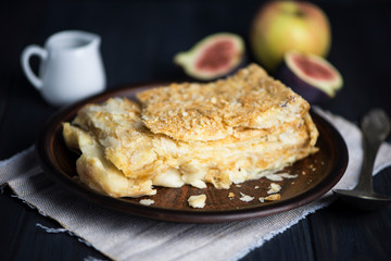 piece of delicious Napoleon cake with vanilla custard on a dark wooden background