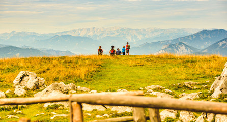 Family sitting on grass and enjoying view over mountains from Schockl in Graz, Austria