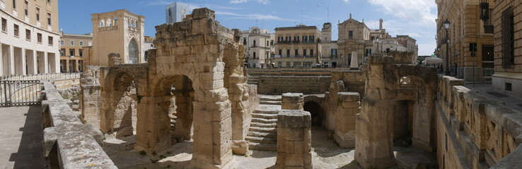Fototapeta na wymiar Lecce – St Oronzo Square. It includes : the Roman amphitheater ; the St Oronzo Column ; the Sedile palace was the ancient seat of the Town Hall ; St Mark Church ; Bank of Italy palace