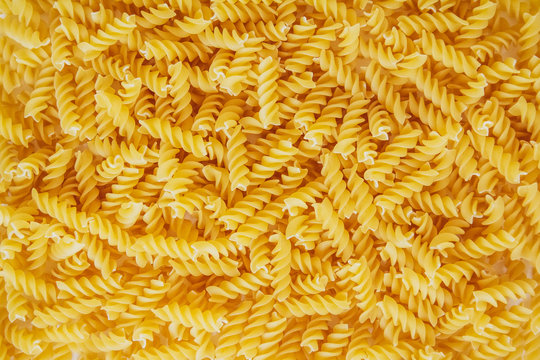 Fusilli pasta as background image. Image texture spiral macaroni. Top view. Copy, empty space for text