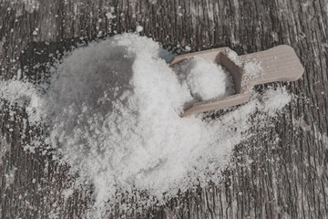 Slide salt on an old wooden table with a wooden spoon, close-up