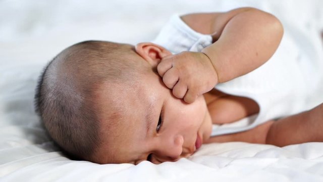 slow-motion of baby lying on a bed at home