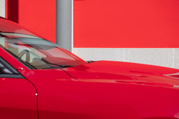 Coche rojo aparcado junto a una pared roja