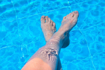 Feet of a woman on the swimming pool