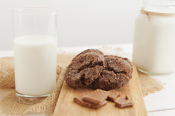 Milk glass and biscuit cookies with kitchen cloth on light background
