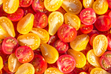 Fresh halves of Brazilian cherry tomatoes. Background of many colorful cherry tomatoes. Sliced yellow and red cherry tomatoes. Cherry tomatoes top view.