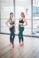 Two young women standing in bright fitness studio