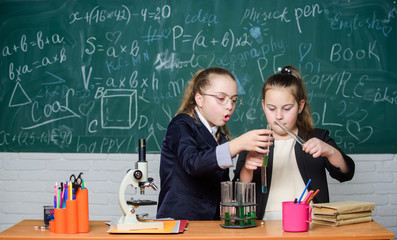 Make studying chemistry interesting. Educational experiment concept. Microscope and test tubes on table. Be careful performing chemical reaction. Basic knowledge of chemistry. Girls study chemistry