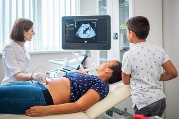Pregnant woman and her son on utltrasonographic examination at hospital