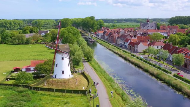 Aerial over canal and small town of Damme, Belgium and historic windmill.